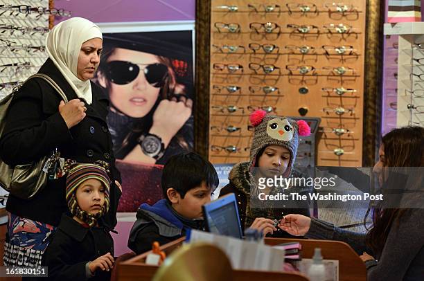 Nadia Qasim, from Pakistan, watches over her family as they're helped by clerk Nancy Albaiza, R, of El Salvador, during a visit to the eye doctor at...