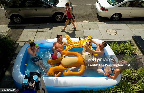 Residents from left to right, Eric Lashner, Sam Mullins, David Knight, and Megan Schuller beat the heat while cooling off in a baby pool set up at...