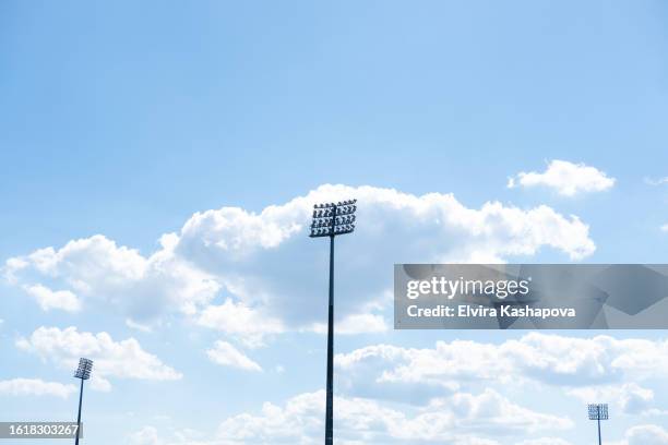stadium lights during the day against a blue sky with clouds, copy space - reflector objeto fabricado fotografías e imágenes de stock
