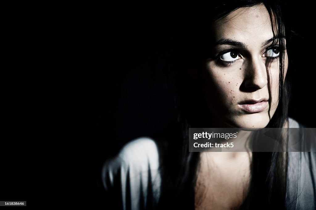 A girl in the dark looking up with an apprehensive look