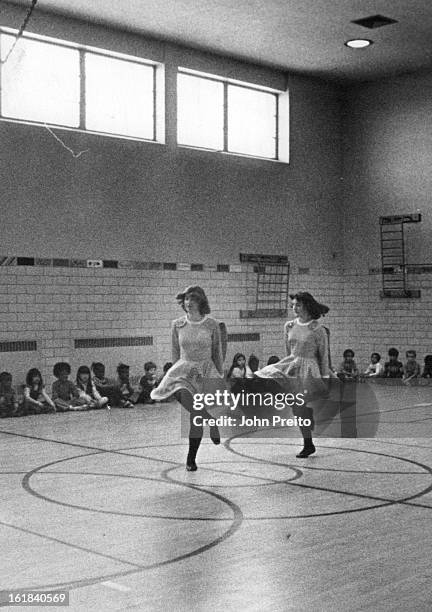 Irish Stepdancers Of Colorado Entertain Students; Jessica Roybal, first grader at Slavens Elementary, leans out on her elbow to get better view of...