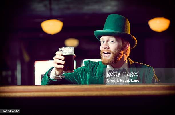 irish character / leprechaun toasting with a pint of beer - leprechaun stockfoto's en -beelden