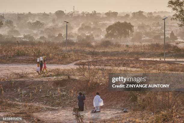 Men pray on a vacant lot early in the morning during Zimbabwe's presidential and legislative elections in Bulawayo on August 23, 2023. Zimbabweans on...