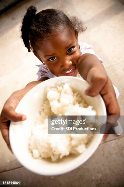 young girl holding up a bowl of rice - rice food staple stockfoto's en -beelden