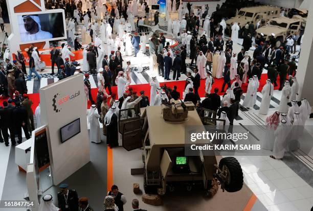 People walk past a US-made armoured vehicle during the opening of the International Defence Exhibition and Conference at the Abu Dhabi National...