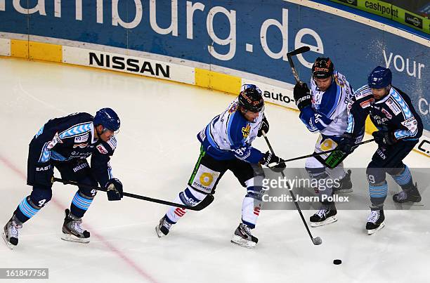 Eric Schneider and Robert Collins of Hamburg and Rene Roethke of Straubing compete for the puck during the DEL game between Hamburg Freezers and...
