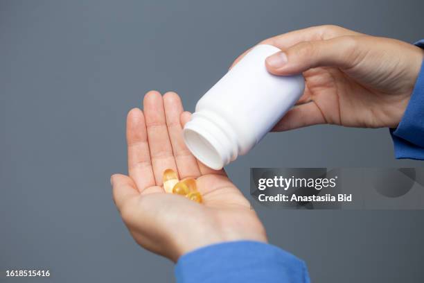 closeup photography of female hands,holding blank medical jar and omega capsules in the hand. - brain in a jar stock pictures, royalty-free photos & images