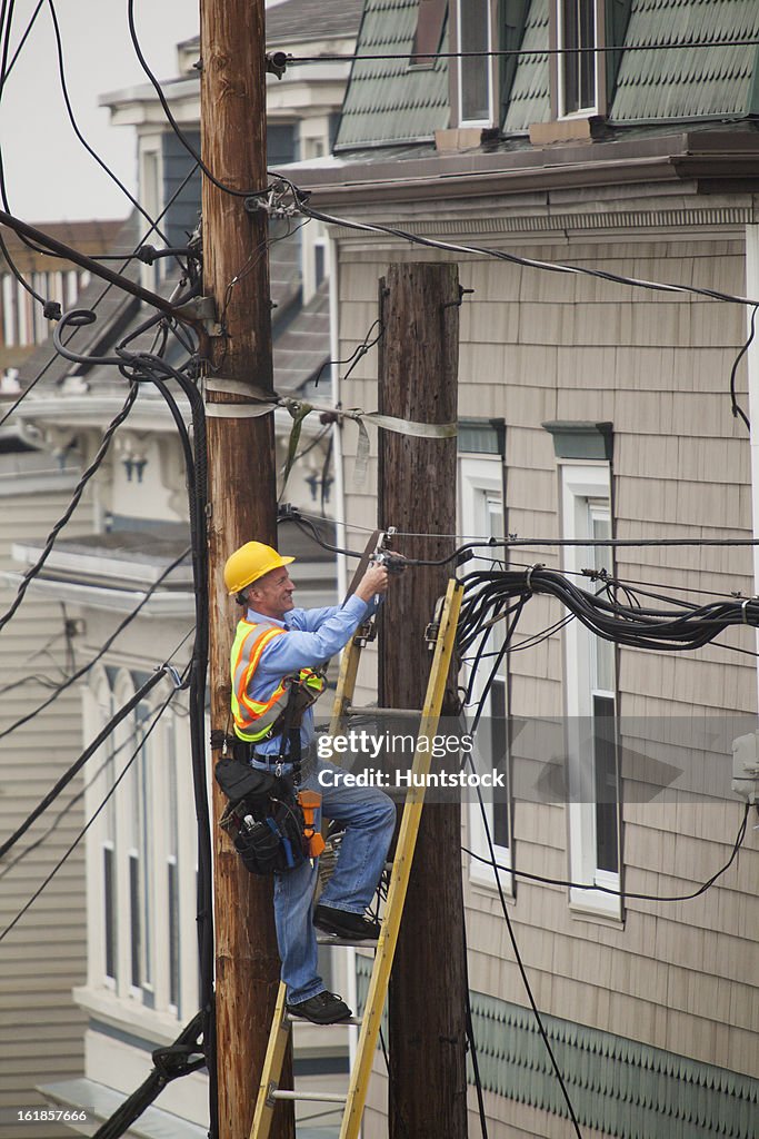 Cable lineman installing a filter on city power poles