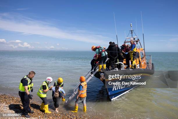 Families are helped ashore on Dungeness beach after being rescued in the English Channel by the RNLI on August 16, 2023 in Dungeness, England. Over...