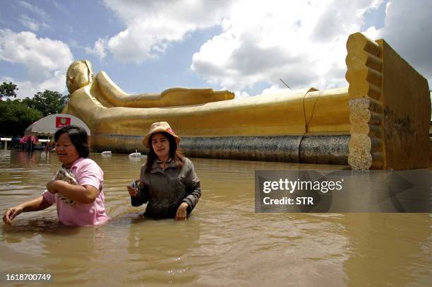 Villagers walk through flood water in front a giant buddha statue in Ayutthaya province on October 19, 2010. Flash floods have killed at least seven...