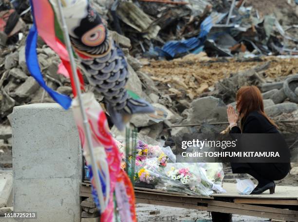 Mother prays for her missing child at the Okawa elementary school in the tsunami-devastated city of Ishinomaki, Miyagi prefecture on May 11, 2011....