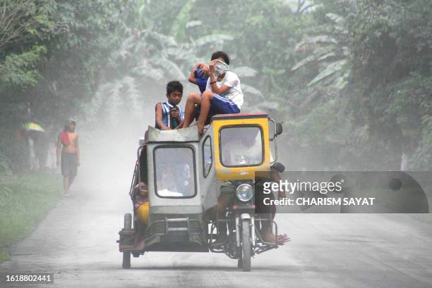 Children on a motorised tricycle cover their faces to avoid inhaling ash after Mount Bulusan volcano, Bulusan, 250 kilometres southeast of the...