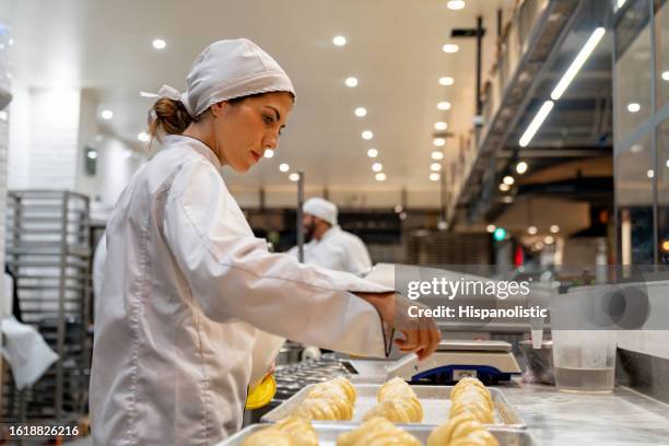 donna che lavora in una panetteria che fa croissant - fabbrica di produzione alimentare foto e immagini stock