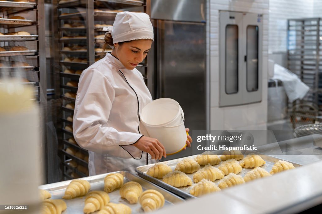 Happy baker spreading coconut on some croissants
