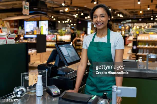 glückliche frau, die an der kasse in einem supermarkt arbeitet - black woman on cash register stock-fotos und bilder