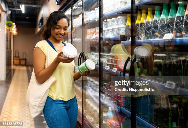 woman shopping at the supermarket and comparing two products - sportswear shopping stockfoto's en -beelden