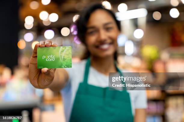 cashier at a supermarket holding a loyalty card - loyalty card stock pictures, royalty-free photos & images
