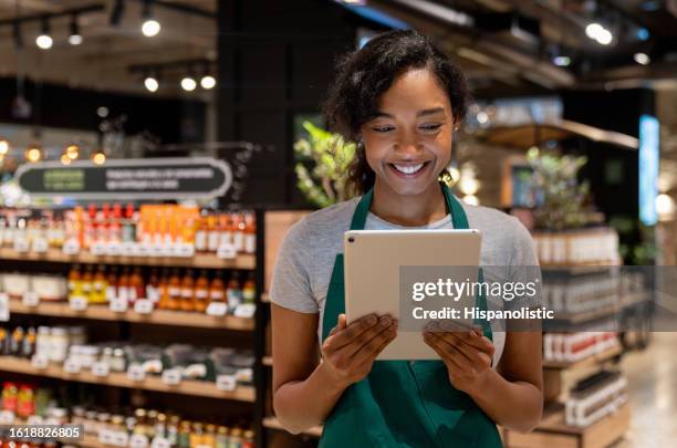 einzelhandelsangestellte, die in einem supermarkt mit einem digitalen tablet arbeitet - supermarkt gang stock-fotos und bilder