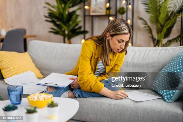 young woman checking her finances at home - home finances stock pictures, royalty-free photos & images