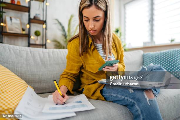 une jeune femme vérifie ses finances à l’aide d’un smartphone - formulaire des impôts photos et images de collection