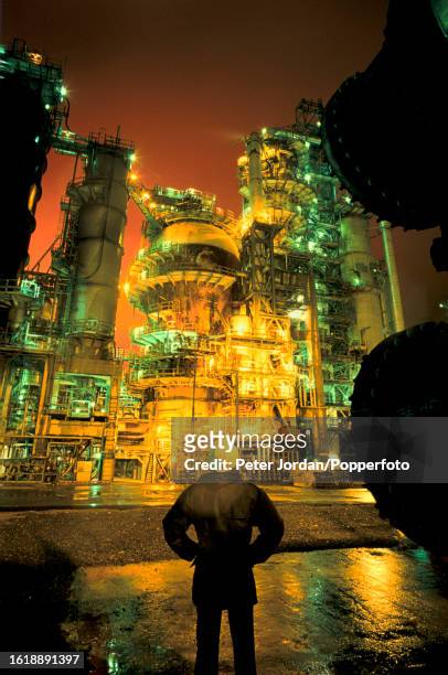 Night time view of the fluid catalytic cracking unit in operation at Pembroke oil refinery, owned by the Texaco oil company, on the south bank of...