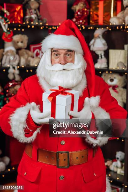 santa claus holding a christmas gift on the background of toys - atelier pere noel photos et images de collection