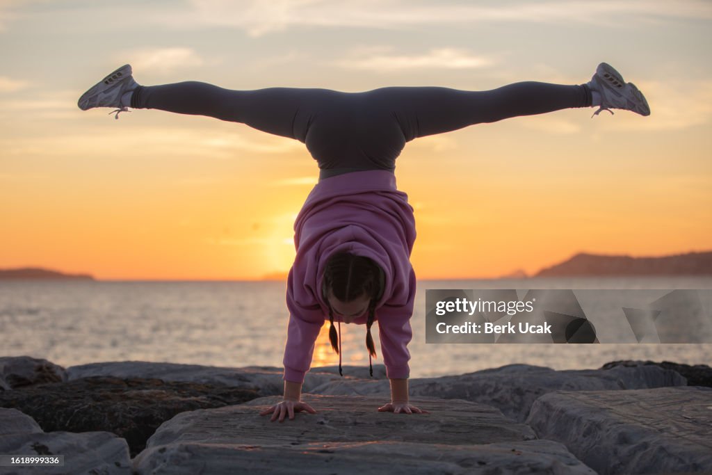 Female athlete is exercising on the outside at sunset.