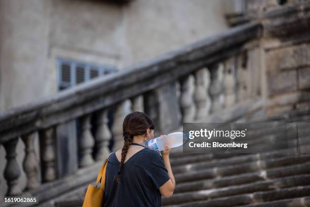 Tourist cools themselves with a bottle of water as they climb the steps of the Cathedral of Santa Maria during high temperatures in the old town area...