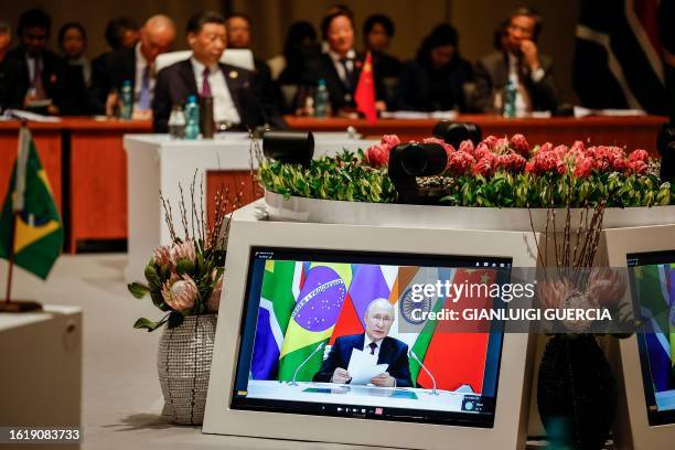 Delegates attend the plenary session as Russian President Vladimir Putin delivers his remarks virtually during the 2023 BRICS Summit at the Sandton...