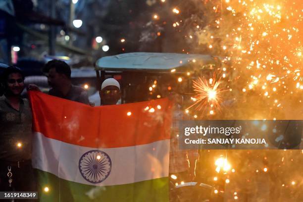 Man holds India's national flag amid firecrackers at a street in Prayagraj on August 23 to celebrate the successful lunar landing of Chandrayaan-3...