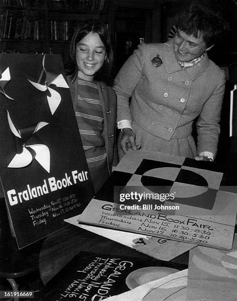 Posters Tell of Christmas Book Sale; Graland student, Emmy Bunker, looks over posters of Graland Country Day School Book Fair with Mrs. Philip Emery....