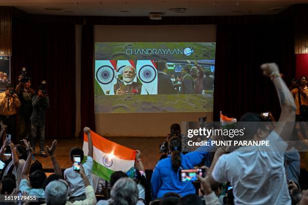 People wave India's national flag as India's Prime Minister Narendra Modi congratulates the Indian Space Research Organisation for the successful...