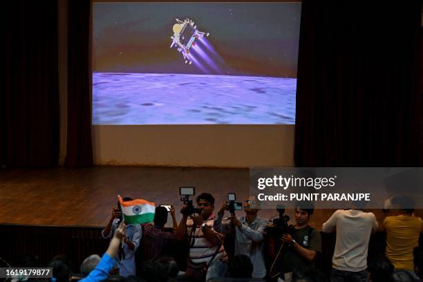 People watch a live stream aired by Indian Space Research Organisation website at the Nehru Science Centre in Mumbai on August 23 minutes before the...