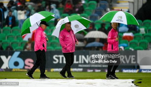 Dublin , Ireland - 23 August 2023; Umpires, from left, Mark Hawthorne, Jareth McCready and Paul Reynolds inspect the covers and outfield as rain...