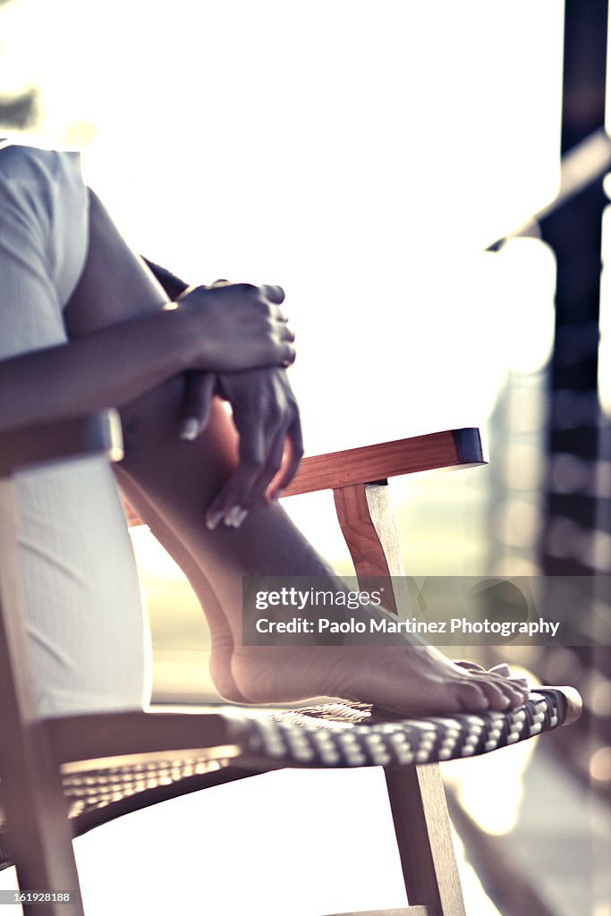 Feet and hands details of girl sitting on a chair