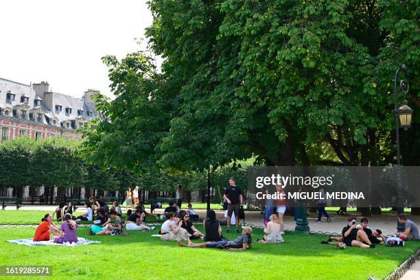 Graphic content / People enjoy Place des Vosges, originally Place Royale, which is the oldest planned square in Paris, on August 23 as temperatures...