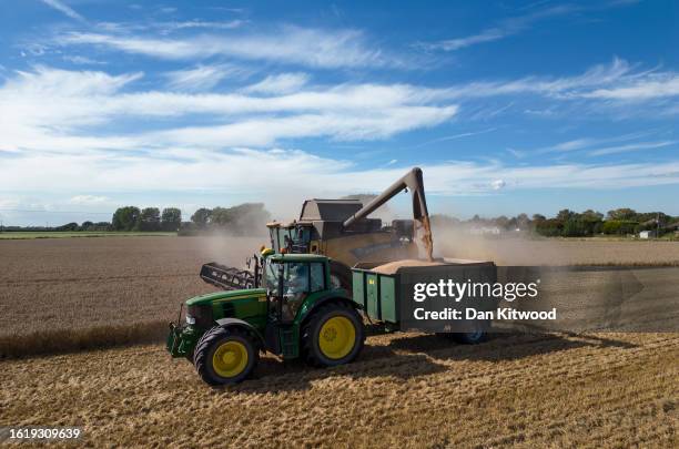 An aerial view of farmers harvesting a crop in fields on August 16, 2023 in New Romney, England. After recent wet weather the annual harvest had made...