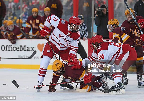Seth Ambroz of the Minnesota Golden Gophers is shoved to the ice by Joe Faust and Nic Kerdiles of the Wisconsin Badgers during the Hockey City...