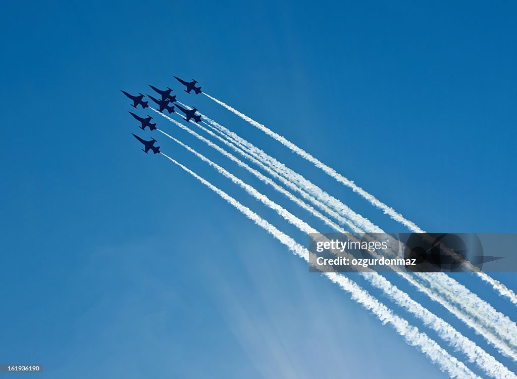 シルエットに 7 面の戦闘機、煙の航空ショー