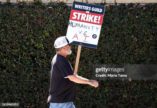 Sign reads 'Humanity vs. AI' as striking members picket outside Warner Bros. Studio on August 16, 2023 in Burbank, California. The Writers Guild of...