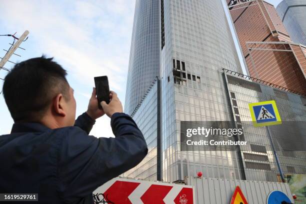 Man takes a photo of a damaged building of the Moscow-City business center after a drone fell on August 23 in Moscow, Russia. The Russian Defence...