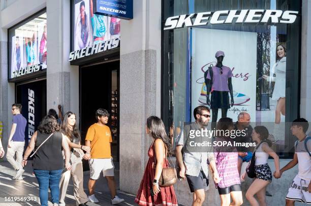 Pedestrians and shoppers walk past the American lifestyle and performance footwear brand Skechers store in Spain.