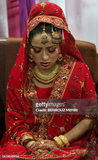Pakistani bride Najma Khalil folds her hands decorated with henna and jewellery while wearing the Lehenga wedding cloth at her wedding party in...