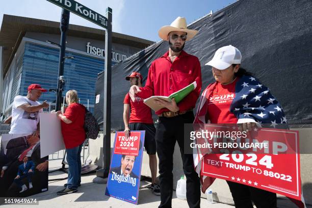 Supporters of former US President and 2024 Presidential hopeful Donald Trump carry signs depicting Florida Governor and 2024 Presidential hopeful Ron...