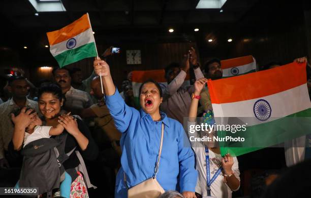 People wave India's national flag as they celebrate the soft landing of Chandrayaan-3 spacecraft on the moon's south pole, in Mumbai, India, 23...