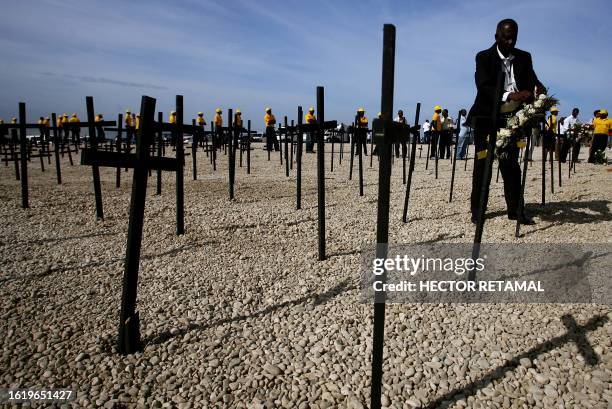 Man places flowers on a cross at St. Christophe, where thousands of victims of the January 12, 2010 earthquake are buried, in Port-au-Prince on...