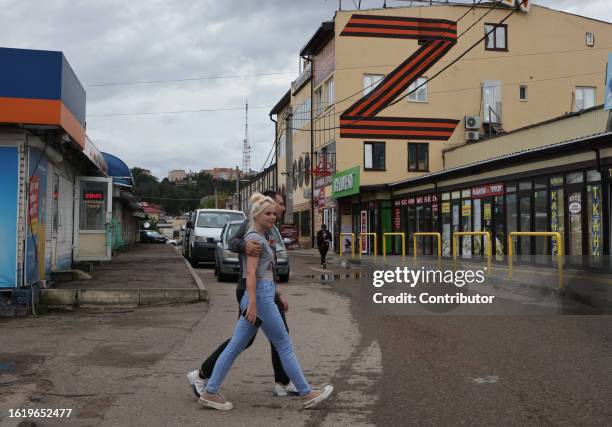 People walk past a street market as a giant letter "Z", a symbol of pro-war propaganda, is seen on the building on August 22 in Smolensk, 395...