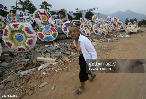 Man walks past wreaths of flowers layed in memory of children killed when their school collapsed during an earthquake in the Jiulong township of...