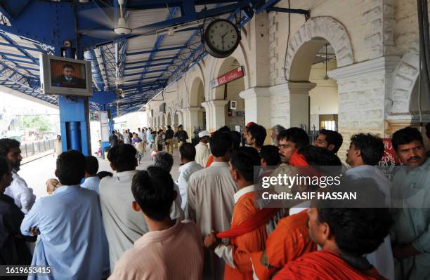 Pakistani men watch the television broadcast of Pakistani President Pervez Musharraf addressing the nation at the railway station in Karachi on...