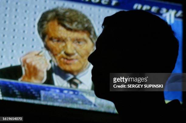 Man looks to the TV screen and listens to Viktor Yushchenko, leader of the opposition, during TV debates with Ukraine's Prime minister Victor...